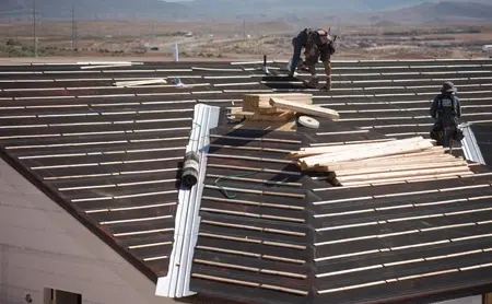 Roofers installing a new roof with underlayment and wood battens on a building in Fontana.